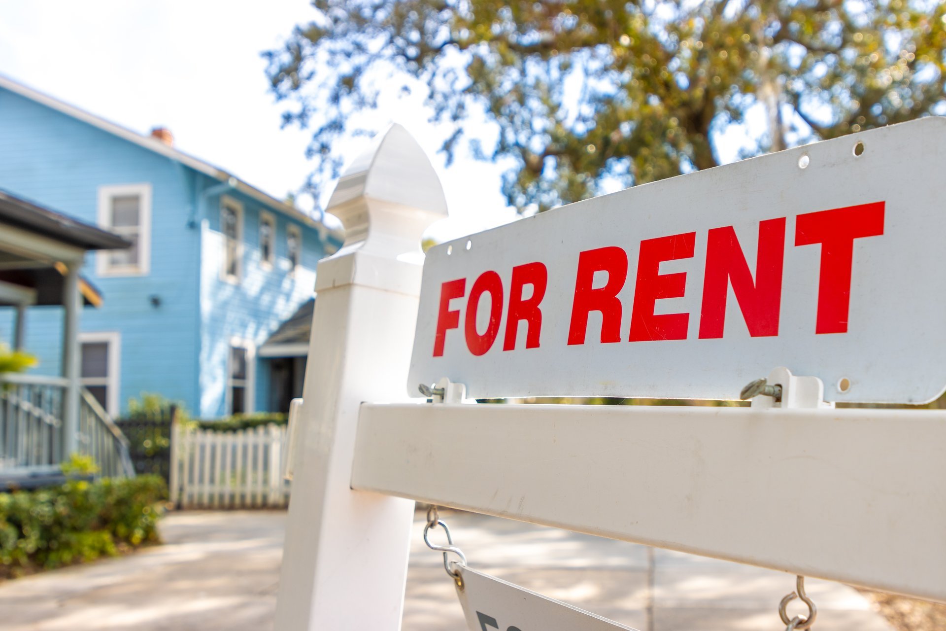 A white and red sign advertises a house for rent