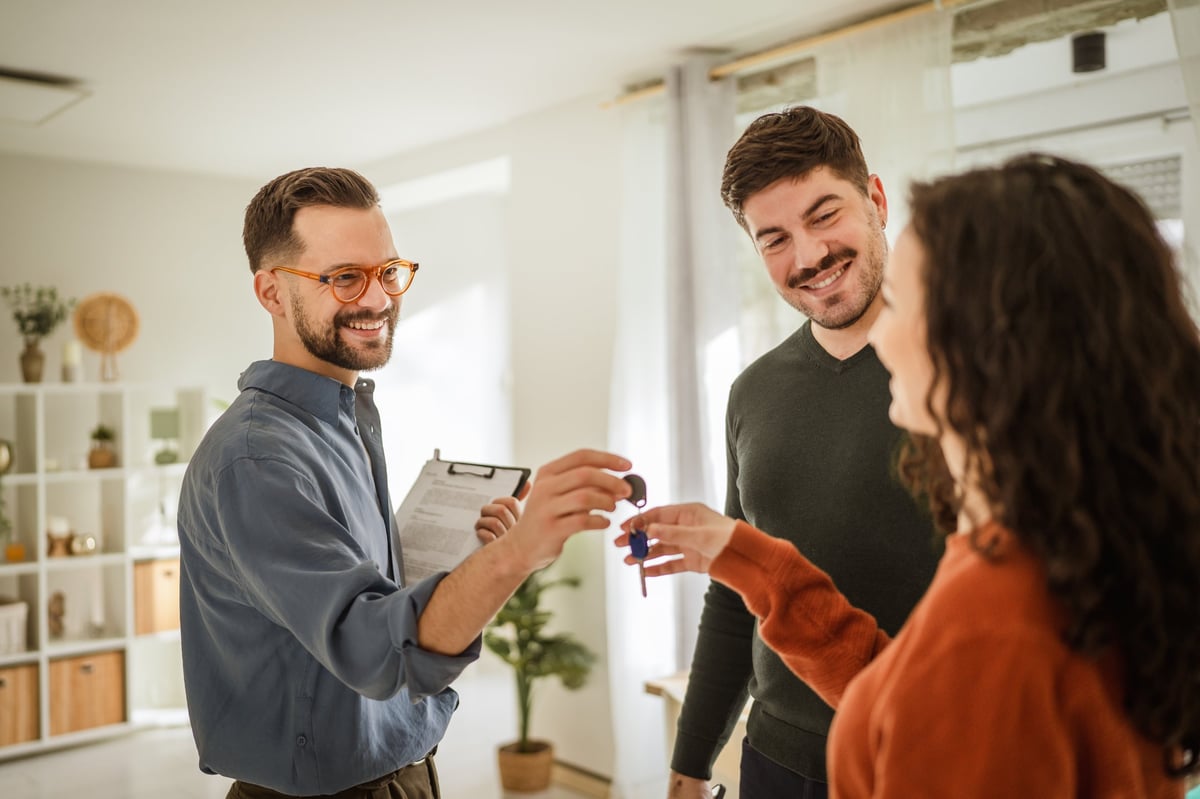Real estate agent handing keys to happy new homeowners