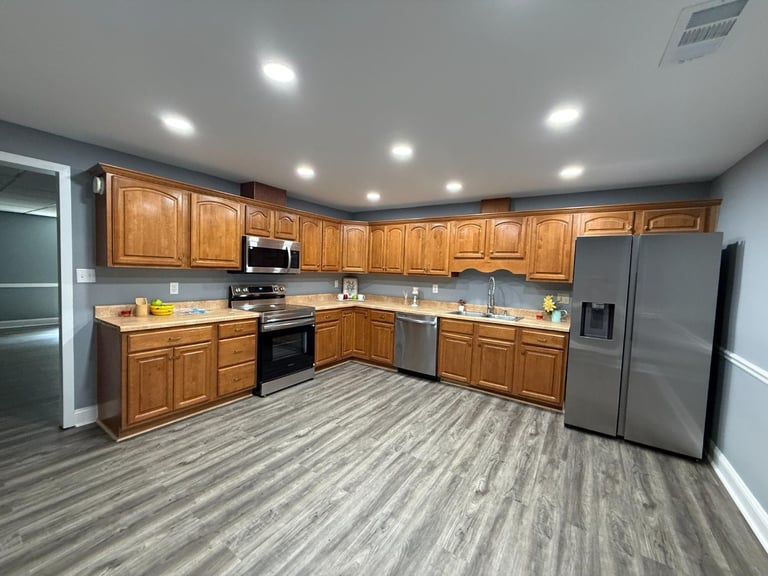 Modern kitchen with wooden cabinets, stainless steel appliances, gray wood-look flooring, and recessed lighting