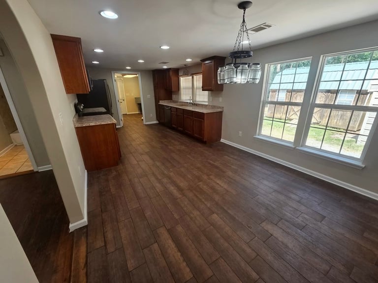 Modern kitchen and dining area with dark wood cabinets, hardwood flooring, and large windows with natural light