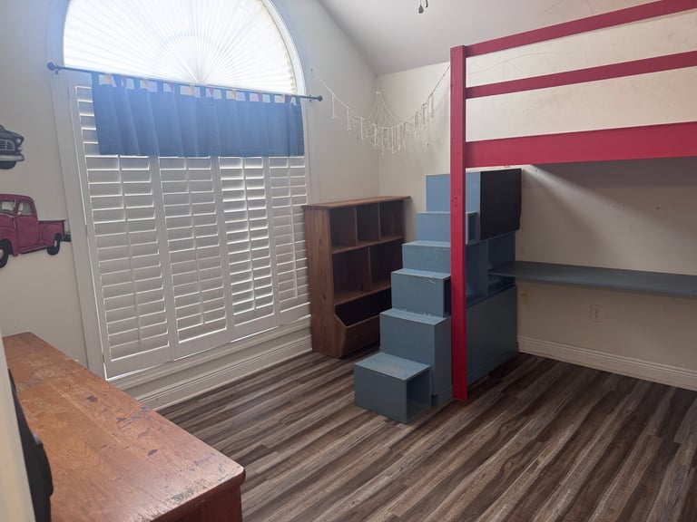 Childs bedroom with loft bed, wooden shelving, striped flooring, and red and blue accents on walls
