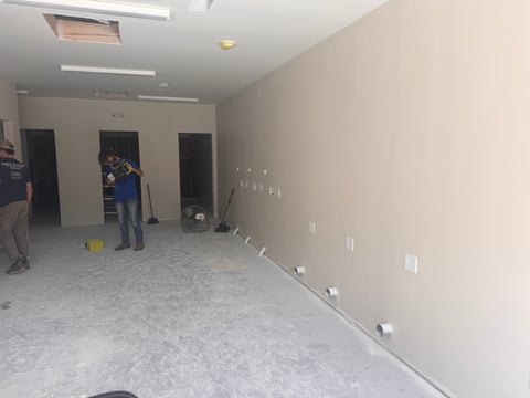 Empty interior construction space with white drywall walls, recessed lighting, and outlet boxes — new bathroom and shower facilities under construction