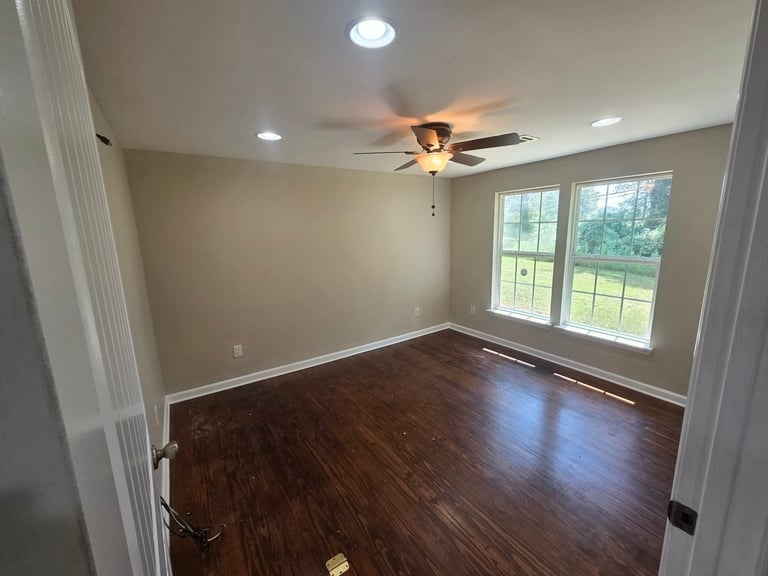 Empty room with dark hardwood flooring, ceiling fan, recessed lighting, and large windows overlooking outdoor landscape